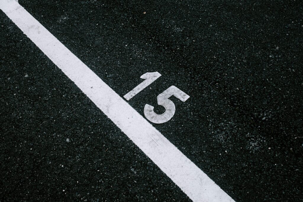 Close-up of a white diagonal road line painted on dark, textured asphalt.